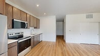 Located at 4300 W Brown Deer Rd in Brown Deer, WI, this single-floor unit offers a well-designed, efficient layout that maximizes every square foot. The open-concept kitchen and living area form the heart of the space, combining functionality with a clean, modern aesthetic. The kitchen is outfitted with a full suite of stainless steel appliances — including a refrigerator, electric range, over-the-range microwave, and dishwasher — complemented by warm-toned wood cabinetry, light countertops, a tile backsplash, and a single-basin sink. Recessed lighting illuminates the kitchen and living area, enhancing the bright, airy feel of the space. Warm-toned light hardwood flooring runs consistently throughout, adding cohesion and a sense of openness. The spacious primary bedroom offers a generous footprint, a large window that invites natural light and neighborhood views, and access to a dedicated closet for ample storage. Crisp white walls and clean-lined trim throughout contribute to the space's fresh, modern character. The overall layout flows logically from the open living and kitchen zone through a hallway to the private bedroom, making the unit both practical and comfortable.