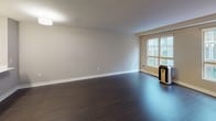 Located at 211 Lenora St, Unit 410 in Seattle, WA, this single-floor residence features a thoughtfully designed open-concept layout. Dark hardwood flooring flows consistently throughout the living spaces, lending a sleek and cohesive aesthetic.

The kitchen is well-appointed with dark cabinetry, white quartz countertops, stainless steel appliances, and a marble-style tile backsplash. A kitchen island with pendant lighting above provides both additional workspace and a natural transition into the open living area. The living room is generously proportioned with neutral-toned walls and large windows that allow natural light to fill the space.

The bedroom is a comfortable and quiet retreat, featuring the same rich hardwood flooring, a ceiling fan with light fixture, and windows that bring in natural light. A baseboard heating unit ensures year-round comfort.

The bathroom is finished with a dark-cabinet vanity, white quartz countertop, an undermount sink, a large mirror with overhead lighting, a wall-mounted storage cabinet, and a full soaking tub with tiled surround. The hallway connecting the rooms offers a clean, open transition between living and private areas. Overall, the unit presents a modern urban aesthetic with quality finishes throughout.