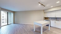 This 1-bedroom, 1-bathroom corner unit at Mayala in Pompano Beach, Florida offers a thoughtfully designed, open-concept layout finished with consistent wood-look tile flooring throughout. The living and dining area is bright and airy, featuring neutral warm-toned walls, clean white baseboards, and track lighting that enhances the open feel of the space. Sliding glass doors lead to a private balcony with views of the surrounding community.

The kitchen is well-appointed with crisp white shaker-style cabinetry extending to the ceiling, providing ample storage. A gray subway tile backsplash adds a modern touch, while stainless steel appliances — including a refrigerator, range, microwave, and dishwasher — offer full functionality. A white kitchen island serves as both a prep surface and casual dining area.

The bedroom is generously sized and includes its own sliding glass door access to the balcony, filling the room with natural light. A spacious walk-in closet with built-in shelving and hanging rods provides excellent storage capacity.

The bathroom features a white vanity with quartz-style countertop, an illuminated LED mirror, and a full soaking tub with tiled surround, all finished in a clean, contemporary palette that ties the unit together cohesively.
