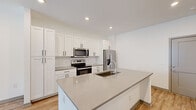 Located on Golden Alexander St SW in Wyoming, Michigan, this single-story, one-bedroom, one-bathroom unit offers a well-organized layout designed to maximize its compact footprint. Light wood-look flooring runs consistently throughout every room, creating a cohesive and clean aesthetic that enhances the sense of openness.

The kitchen serves as a central highlight, featuring white shaker-style cabinetry extending to the ceiling for ample storage, a subway tile backsplash, and quartz countertops in a warm gray tone. A central island with an undermount sink provides additional workspace and casual seating potential. Stainless steel appliances, including a French door refrigerator with ice dispenser, electric range, and over-the-range microwave, complete the modern kitchen setup.

The living room is bright and airy, benefiting from a large window that allows natural light to fill the space. A ceiling fan with a light fixture adds both function and comfort. The bedroom is a comfortable size, also featuring a window with outdoor views, a ceiling fan, and a dedicated closet for storage.

The bathroom includes a white vanity with quartz countertop, undermount sink, framed mirror, and wood-look flooring consistent with the rest of the unit. A hallway connects the main living areas, providing a logical and efficient flow throughout the space.