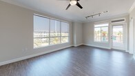 Located at 2120 E Katella Ave in Anaheim, California, this single-floor unit presents a clean, contemporary design with a neutral color palette and consistent finishes throughout. The open-concept living and kitchen area serves as the heart of the space, where wood-look flooring, crown molding, and a ceiling fan establish a polished atmosphere. A kitchen island with granite countertops anchors the layout, complemented by light wood cabinetry, stainless steel appliances including an over-the-range microwave, and a black gas range. Industrial-style pendant lights add a modern accent above the island.

The living area features large windows fitted with roller shades, track lighting, and a ceiling fan, allowing ample natural light and views of surrounding palm trees. Bedrooms are carpeted for comfort, each equipped with ceiling fans and roller-shaded windows or sliding glass doors that open to views of palm trees and the surrounding Anaheim landscape.

The bathroom is finished with wood-look flooring, a light wood vanity topped with granite, a large mirror, and a full soaker tub with a curved shower rod. The overall design is cohesive, functional, and well-suited to the Southern California setting.