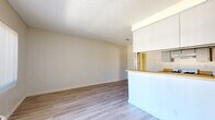 Located at 8541 Foothill Blvd in Los Angeles, CA, this one-bedroom, one-bathroom unit offers a practical and efficient single-level layout. The open-concept living and kitchen area serves as the heart of the home, where light wood-style laminate flooring extends throughout and a textured ceiling adds subtle character. A pass-through counter connects the living room to the galley-style kitchen, which features gray cabinetry on both sides, warm butcher block countertops, a gas range, and a stainless steel sink — providing a well-organized cooking space with generous storage. Vertical blinds on the living room window allow natural light to filter in while maintaining privacy, and a wall-mounted PTAC unit provides in-unit climate control. The bedroom is carpeted for comfort, benefits from its own window with vertical blinds, and includes a built-in sliding-door closet for convenient storage. The bathroom is clean and functional, offering a vanity with white cabinetry, a toilet, and a tub-shower combination enclosed with sliding glass doors. Wood-style flooring continues into the bathroom, maintaining a cohesive look throughout. A hallway connects the main living areas to the bedroom and bathroom, completing this efficiently designed unit.