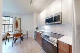 Located at 1100 Dahlia St NW in Washington, DC, this well-appointed 2-bedroom, 2-bathroom unit offers a thoughtfully designed layout across a single floor. Light hardwood flooring flows seamlessly throughout, lending a clean, contemporary aesthetic to every room.

The kitchen is outfitted with stainless steel appliances including a range, microwave, and dishwasher, complemented by white upper cabinetry, warm wood lower cabinets, and a classic white subway tile backsplash. It opens directly into a combined dining and living area, creating an efficient and sociable floor plan.

Both bedrooms feature windows that invite natural light and offer exterior views. The primary bedroom is comfortably sized and includes a dedicated closet. The second bedroom also benefits from natural light and a closet of its own.

The two bathrooms are finished with warm wood vanities and white quartz countertops. One bathroom features a tiled shower-tub combination, while the other includes a glass-door shower, providing distinct options for residents.

A hallway connects the main living spaces to the bedrooms and bathrooms, with an in-unit laundry area adding everyday convenience. The unit's neutral palette, modern fixtures, and efficient use of space make it a practical and attractive home in Washington, DC.