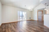 Located at 5008 Gordon Ave in Monona, Wisconsin, this well-appointed two-bedroom, two-bathroom single-floor home offers a comfortable and functional layout with quality finishes throughout. The open-concept kitchen and living area serves as the heart of the home, where rich dark cabinetry pairs with granite countertops and a breakfast bar illuminated by pendant lighting. Stainless steel appliances, including a range, microwave, and dishwasher, complete the kitchen. The living room features warm hardwood-style flooring, a vaulted ceiling, a chandelier, and sliding glass doors that open to a private balcony, filling the space with natural light. The spacious primary bedroom includes a tray ceiling with a ceiling fan, plush carpeting, a dedicated closet, and ample room to move comfortably. The second bedroom also features hardwood-style flooring and a natural light-filled window. Both bathrooms are well-sized, with one featuring a full tub-shower combination. A convenient entry hallway with closet storage connects the living spaces. Consistent warm-toned wood trim and neutral wall colors create a cohesive, inviting ambiance throughout the home.