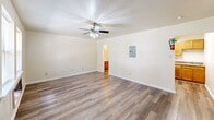 Located at 3401 Garden Oaks Dr in New Orleans, LA, this efficiently designed single-floor unit offers a practical and functional layout encompassing a living room, kitchen, bathroom, and closet. The living room serves as the heart of the space, finished with durable wood-look laminate flooring that runs throughout the unit. A ceiling fan with an integrated light fixture anchors the room, while multiple windows with blinds invite generous natural light and views of the surrounding exterior. The textured ceiling and clean white walls create a bright, neutral ambiance. An electrical panel is conveniently housed within the living area. The kitchen is thoughtfully appointed with warm honey-toned wood cabinetry, both upper and lower, providing ample storage. A granite-look countertop, stainless steel sink, and a white electric coil-top range complete the functional cooking space, all set on the same wood-look flooring. The bathroom features a full tub and shower combination with tiled surround and chrome fixtures. A dedicated closet offers a full-width hanging rod and shelving, making efficient use of the available space. Overall, the unit presents a clean, move-in ready atmosphere with cohesive finishes throughout.