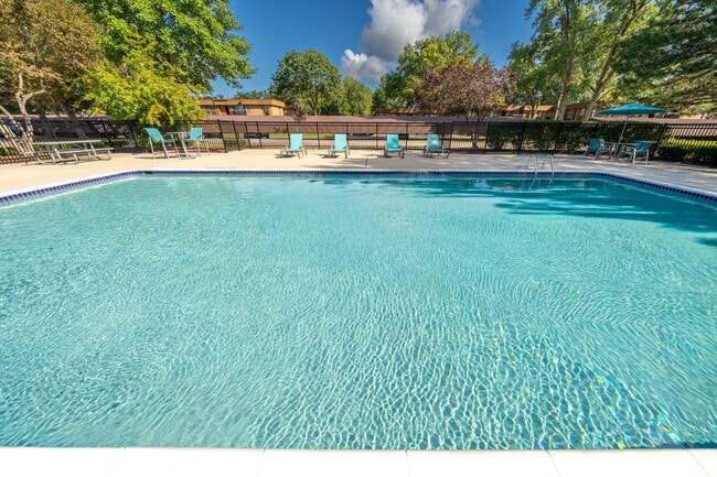 Heated pool equipped with comfy lounge chairs at Westwood Village Apartments in Westland, MI - Westwood Village Apartments