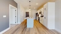 Located in the Shadow Creek community in Jackson, Tennessee, this single-floor residence offers a clean, modern aesthetic with thoughtfully chosen finishes throughout. Light-toned wood-look flooring runs continuously across the living spaces, creating a cohesive and bright interior atmosphere.

The kitchen serves as a central hub of the layout, featuring a spacious island with a built-in sink, pendant lighting, crisp white shaker cabinetry with matte black hardware, and stainless steel appliances including a range, microwave, and refrigerator. Recessed lighting adds a polished touch overhead.

The living and bedroom areas are bright and open, each equipped with ceiling fans and large windows fitted with horizontal blinds that allow for ample natural light. The neutral cream-toned walls provide a versatile backdrop throughout the space.

The entryway is anchored by a distinctive dark wood front door with matte black hardware, accompanied by an electrical panel and an interior door with louvered ventilation detail — a functional and well-organized transition point into the home.

The bathroom is finished with warm wood-look flooring, a dark espresso vanity with white countertop, a tub-shower combination with tiled surround, and clean white walls. The overall design of this residence balances practicality with contemporary style in a well-appointed single-level floor plan.
