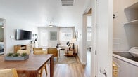 This single-story residence offers a well-organized layout across four bedrooms, two bathrooms, a combined kitchen and living area, two closets, and two hallways. Wood-look plank flooring runs consistently throughout the home, lending warmth and visual continuity from room to room.

The open-concept kitchen and living area serves as the heart of the home. The kitchen is outfitted with flat-front cabinetry in a warm wood tone, white quartz countertops, stainless steel appliances including a dishwasher and range, and a window above the sink that allows natural light to fill the space. The adjoining living area is bright and welcoming, with multiple windows, a ceiling fan, and direct access to an outdoor area via a glass-panel door.

The primary bedroom is a comfortable retreat featuring a ceiling fan, a window with natural light, and access to a private en-suite bathroom. The en-suite includes a walk-in shower, a wood-toned vanity with white countertop, and a walk-in closet with built-in shelving and hanging rods. A second full bathroom mirrors the design aesthetic with a tub-shower combo, matching vanity, and a window for natural light. The remaining bedrooms are well-proportioned and share the home's consistent, neutral-toned finishes.