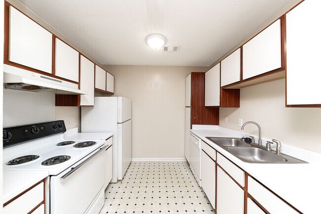 Cocina con electrodomésticos blancos, armarios de madera y amplio espacio en la encimera. - Creekside