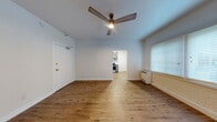 Located at 260 S Mariposa Ave in Los Angeles, CA, this efficiently designed single-floor unit offers a thoughtful layout comprising a living room, kitchen, bathroom, closet, and hallway. The living room is bright and open, highlighted by warm wood-look flooring, white-painted exposed brick accent walls, and a ceiling fan with integrated lighting. Natural light filters in through horizontal-blind-covered windows, creating an airy atmosphere. A wall-mounted heater provides functional comfort. The space flows through an arched doorway into the kitchen, which features modern gray shaker-style cabinetry, white subway tile backsplash, a stainless steel gas range, under-cabinet range hood, and a stainless steel sink with contemporary faucet — all set against the same warm wood-look flooring that runs throughout. The bathroom offers a refined aesthetic with floor-to-ceiling marble-look tile, a soaking bathtub, a frosted glass window for natural light and privacy, and a clean white vanity with sink. A hallway connects the rooms and includes access to a dedicated closet for storage. The overall design balances modern updates with practical features, making this a well-appointed urban unit in the heart of Los Angeles.