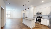 Located in the desirable Roxborough neighborhood of Charlotte, NC, this well-appointed 1-bedroom, 2-bathroom home offers a thoughtfully designed single-floor layout that maximizes both comfort and functionality. Warm hardwood-style flooring flows consistently throughout the space, creating a cohesive and inviting ambiance.

The open-concept kitchen is a standout feature, showcasing white shaker cabinetry, granite countertops, a subway tile backsplash, stainless steel appliances, and a central island with a built-in sink illuminated by stylish pendant lighting. The adjacent living room is bright and spacious, benefiting from large windows that invite ample natural light.

The generously sized primary bedroom features a ceiling fan, large windows with exterior views, and direct access to a well-organized walk-in closet with built-in shelving and hanging rods. The primary bathroom is elegantly appointed with a soaking tub, glass-enclosed shower with large-format subway tile, a granite-topped dual vanity with gray cabinetry, and light tile flooring. A second full bathroom provides additional convenience.

Practical amenities include two dedicated laundry areas equipped with stacked washer and dryer units. Clean white walls, modern fixtures, and consistent finishes throughout reflect a contemporary design sensibility.