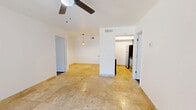 This 2-bedroom, 2-bathroom single-floor residence offers a functional and well-designed layout that maximizes its footprint. The open-concept living, dining, and kitchen area forms the heart of the home, finished with warm travertine tile flooring and anchored by a ceiling fan overhead. Colorful pendant lights hang above a granite-topped breakfast bar, which separates the living space from the kitchen. The kitchen is equipped with stainless steel appliances, including a refrigerator, range, and microwave, complemented by dark cabinetry for a modern contrast.

The primary bedroom features rich hardwood-style flooring, a ceiling fan with light fixture, and a window dressed with blinds that allows natural light to filter in. The second bedroom mirrors a similar layout and shares the same clean, neutral aesthetic throughout. Each bedroom is served by its own dedicated closet for added storage convenience.

Both bathrooms are finished with white tile surrounds and include a shower-tub combination with chrome fixtures and granite-accented vanities. The overall design is clean and neutral, with white walls throughout that create a bright, open atmosphere. The space offers a practical and comfortable layout suitable for everyday living.