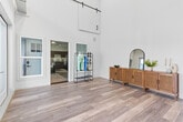 Located at 2315 South 11th Avenue in Bozeman, MT, this one-bedroom, one-bathroom unit offers a well-designed single-floor layout with a variety of impressive architectural details. The entrance immediately sets the tone with dramatic floor-to-ceiling glass doors that flood the space with natural light and soaring double-height ceilings that create an airy, open atmosphere. Light wood-style flooring runs throughout the main living areas, complementing the bright, neutral palette.

The open-concept area seamlessly connects the living room, dining space, and kitchen. The living room features large windows for additional natural light, while the kitchen is outfitted with rich dark cabinetry, granite-style countertops, and a full suite of stainless steel appliances including a refrigerator, range, microwave, and dishwasher. Track lighting enhances the kitchen's functionality.

The spacious bedroom is finished with plush carpet, a window for natural light, and direct access to a dedicated closet. The bathroom features a dark vanity with granite-style countertops, a single undermount sink, and a well-lit mirror. Additional conveniences include an in-unit laundry room. A sliding barn door accent adds a modern-rustic design touch to the main living area.