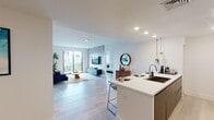 This contemporary single-floor residence is thoughtfully designed with an open-concept layout and a cohesive modern aesthetic throughout. Light hardwood flooring flows seamlessly across the main living areas, lending warmth and continuity to the space.

The kitchen is a standout feature, outfitted with dark wood cabinetry, white quartz countertops, a light blue tile backsplash, and stainless steel appliances. A central island with bar seating connects the kitchen to the open living and dining area, making it ideal for entertaining. The living room is generously proportioned, bathed in natural light from large windows that offer views of the surrounding neighborhood, and anchored by a comfortable seating area.

The primary bedroom is a serene retreat featuring a bold dark accent wall, a natural wood bed frame, and a window with outdoor views. A second bedroom provides ample closet storage. A dedicated office space with a teal accent wall and built-in desk adds valuable functionality.

The bathrooms are each distinctly designed. One features dramatic floor-to-ceiling marble-look tile, a glass-enclosed shower, and a striking large-scale artistic mural as a focal point. The second bathroom offers a soaking tub, large-format tile flooring, and a floating wood vanity. Recessed lighting throughout completes the refined, gallery-like ambiance of this well-curated residence.