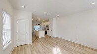 This contemporary 2-bedroom, 2-bathroom townhome in Charlotte, NC offers 1090 square feet of well-designed living space across two floors. The ground floor features an open-concept layout, combining the kitchen, living, and dining areas. The kitchen boasts white cabinetry, stainless steel appliances, and a large island with a sink and seating area. Pendant lights add a touch of modern elegance.

Light-toned wood flooring runs throughout, complementing the crisp white walls and creating a bright, airy atmosphere. Large windows with blinds allow ample natural light to flood the space. The primary bedroom, measuring 160 square feet, includes an en-suite bathroom with a glass-enclosed shower and modern fixtures.

Both bathrooms feature clean lines, white vanities with ample storage, and sleek black hardware. The townhome includes two closets for additional storage. Outside, the property showcases contemporary siding and a small, landscaped front yard. The interior's neutral color palette and modern finishes create a stylish, move-in ready home perfect for urban living.