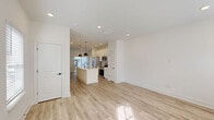 Located in Charlotte, NC, this two-story, 2-bedroom, 3-bathroom home offers a thoughtfully designed layout spread across two floors. The main level features an open-concept living, dining, and kitchen area bathed in natural light from large windows and a glass patio door. The kitchen is a standout, boasting white shaker cabinetry, quartz countertops, a central island with a matte black pull-down faucet, pendant lighting, and stainless steel appliances. Light wood-tone flooring flows seamlessly throughout, enhancing the bright, airy feel of the space. A private patio accessible from the main level extends the living area outdoors. The upper floor houses both bedrooms, including a well-proportioned primary bedroom with an en-suite bathroom and ceiling fan. The bathrooms are elegantly finished with marble-look tile flooring, white vanities, matte black fixtures, and a frameless glass walk-in shower. Five closets provide ample storage throughout the home, while a dedicated laundry area adds everyday convenience. The exterior presents classic gray lap siding with black-framed windows, set within a landscaped community in Charlotte's eastside.