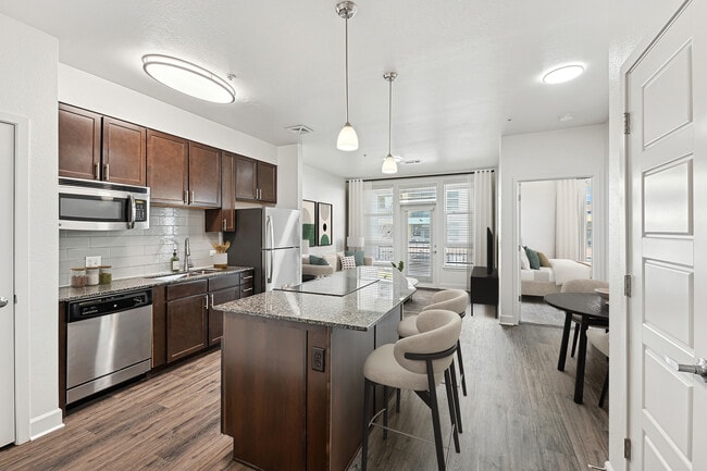 Refreshed Finishes kitchen with espresso cabinetry, speckled granite countertops, grey subway tile backsplash, stainless steel appliances, and hard surface flooring - Avalon Cherry Hills