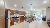 Located at 1517 Cameron Samuel Lane in West Palm Beach, FL, this one-bedroom, one-bathroom residence offers a well-designed single-floor layout that maximizes every square foot. The open-concept kitchen, dining, and living area serves as the heart of the home, creating a seamless flow ideal for everyday living and entertaining. The kitchen is outfitted with rich, warm-toned wood cabinetry, dark granite countertops, stainless steel appliances — including a refrigerator, electric range, and built-in microwave — and a central island with a sink and pendant lighting above. Light tile flooring extends throughout the main living areas, enhancing the bright, airy feel. The living room opens directly to a private balcony through large sliding glass doors, flooding the space with natural light and offering pleasant outdoor views. The bedroom is a comfortable retreat with neutral tones and ample space for a full furniture arrangement. The bathroom features matching granite countertops, wood cabinetry, a full soaking tub with tiled surround, and a large vanity mirror. A hallway connects the living areas to the private spaces, completing this thoughtfully laid-out residence in the heart of West Palm Beach.