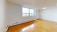 Located on the 12th floor at 250 Lake St in St. Catharines, Ontario, this well-appointed one-bedroom, one-bathroom unit offers a thoughtfully designed layout across a single floor. The open-concept living and dining area is bright and spacious, showcasing warm parquet flooring that flows throughout the main living spaces. Large windows along the exterior wall flood the room with natural light and provide sweeping elevated views, while baseboard heating runs beneath the sills. A private balcony is accessible directly from the living area, extending the sense of openness.

The kitchen is efficiently designed with white cabinetry, subway tile backsplash, dark countertops, and a full suite of stainless steel appliances including a refrigerator, stove, dishwasher, and built-in microwave. A pass-through counter connects the kitchen to the living area, enhancing the open feel.

The generously sized primary bedroom continues the parquet flooring and offers a clean, neutral palette with ample space. The bathroom is finished with large-format stone-look floor tiles, white subway tile surrounding the soaker tub and shower, and a clean vanity with white countertop. A hallway provides practical entry and transition between rooms, completing this comfortable and cohesive urban residence.