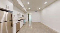 Located at 1503 Venice Blvd in the heart of Venice, Los Angeles, this 1-bedroom, 1-bathroom unit offers a sleek, modern aesthetic defined by clean lines and a minimalist design philosophy. The open-plan kitchen and living area serves as the heart of the unit, featuring polished concrete floors that extend throughout the space, lending an industrial-chic character. The kitchen is outfitted with full-height white flat-front cabinetry, a white quartz countertop, and a complete suite of stainless steel appliances including a gas range, built-in microwave, dishwasher, and refrigerator. Recessed lighting illuminates the space throughout. The bedroom is a well-proportioned, light-filled room with the same polished concrete flooring, crisp white walls, and a dedicated closet. A hallway connects the bedroom to the rest of the unit, also providing access to the in-unit laundry. The bathroom features a full soaking tub with overhead shower, white subway tile surround, a floating vanity with white cabinetry, brushed hardware, and a mirrored medicine cabinet. The overall ambiance is bright, clean, and contemporary, making excellent use of the available footprint.