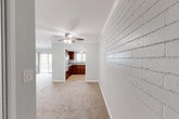 Located in the Clairemont neighborhood of San Diego, this two-bedroom, one-bathroom residence offers a functional and comfortable single-floor layout. The combined living and dining area is generously sized, featuring plush carpeting, a ceiling fan, crown molding, and a distinctive painted brick accent wall that adds character to the space. Vertical blinds and sliding glass doors lead to one of two balconies, allowing natural light to fill the room and offering views of the surrounding neighborhood, including mature palm trees.

The kitchen is well-appointed with rich, dark wood cabinetry, granite countertops, tile flooring, and a full suite of appliances including a gas range and refrigerator. A window above the sink brings in additional natural light.

The primary bedroom is a comfortable size, featuring carpeted floors, a ceiling fan, horizontal shiplap-style accent walls, and its own sliding glass door leading to a private balcony with outdoor views. The second bedroom also features carpet, a ceiling fan, and a mirrored closet. Four closets throughout the unit provide ample storage.

The bathroom is clean and bright, featuring tile flooring, a wood vanity with granite countertop, and a framed mirror. A utility room and hallway round out the thoughtfully organized layout.