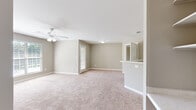 This single-story, 2-bedroom, 2-bathroom home offers a thoughtfully designed layout with a comfortable and neutral aesthetic throughout. The spacious living room features soft carpeting, a ceiling fan with light fixture, and a glass door that invites natural light while providing access to the outdoors. Adjacent to the living area, the kitchen is equipped with white cabinetry, light countertops, a full suite of white appliances including a refrigerator, electric range, and over-the-range microwave, all set atop easy-care hardwood-style flooring. A built-in shelving unit and desk area near the kitchen transition provide added functionality and storage.

Both bedrooms are generously sized, carpeted, and filled with natural light from large windows fitted with blinds. The spacious primary bedroom offers ample room for furnishings, a ceiling fan, and dedicated closet space. The second bedroom is equally well-lit with a wide window overlooking greenery. Two full bathrooms serve the home, one featuring a full soaking tub with a tiled surround. A dedicated laundry room with washer and dryer hookups adds everyday convenience. Two hallways and two closets complete the layout, ensuring practical storage throughout this well-proportioned home.