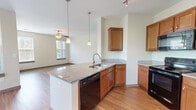 This thoughtfully designed 3-bedroom, 2-bathroom residence spans three floors, with the main living areas occupying the primary level. The open-concept living and dining area is bright and spacious, featuring warm hardwood-style flooring, a ceiling fan with light fixture, and multiple large windows dressed with blinds that fill the space with abundant natural light. A private balcony accessible from the main level offers serene, tree-lined views, creating a peaceful outdoor retreat.

The kitchen is well-equipped and functional, showcasing warm wood cabinetry, granite countertops, a center island with a built-in sink and dishwasher, pendant lighting, stainless steel refrigerator, and a black range. Track lighting adds a modern touch to this practical and attractive cooking space.

The three bedrooms are comfortably sized, with the primary bedroom offering generous dimensions. Bedrooms feature plush carpet flooring and windows that invite natural light. A dedicated closet with wire shelving provides ample storage. The two bathrooms are finished with wood-tone vanities, granite-style countertops, and hardwood-style tile flooring. Connecting hallways are well-lit and efficiently laid out, contributing to the home's smooth flow throughout.