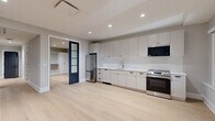 Located on South Broad Street in the heart of Philadelphia, this thoughtfully designed one-bedroom, one-bathroom residence offers a refined living experience with contemporary finishes throughout. Light-toned hardwood flooring flows seamlessly across the entire space, creating a bright and cohesive aesthetic complemented by neutral gray walls and crisp white trim.

The open-concept kitchen is a standout feature, equipped with full-height white shaker cabinetry, a white quartz countertop, a subway tile backsplash, and stainless steel appliances including a refrigerator, electric range, and built-in microwave. A gold-tone gooseneck faucet adds an elegant accent to the undermount sink.

The bedroom is accessed through striking black-framed French doors with frosted glass panels, lending a sophisticated architectural detail to the space. The room includes a built-in closet system with white cabinetry, offering organized and ample storage.

The bathroom is elegantly appointed with a patterned mosaic tile floor, a warm wood-toned vanity with a white countertop, wall-mounted sconce lighting, and a glass-enclosed walk-in shower adorned with textured tile surround and matte black fixtures. A hallway connects the rooms efficiently, completing this well-planned and polished residence.
