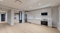 Located on South Broad Street in the heart of Philadelphia, this thoughtfully designed one-bedroom, one-bathroom residence offers a refined living experience with contemporary finishes throughout. Light-toned hardwood flooring flows seamlessly across the entire space, creating a bright and cohesive aesthetic complemented by neutral gray walls and crisp white trim.

The open-concept kitchen is a standout feature, equipped with full-height white shaker cabinetry, a white quartz countertop, a subway tile backsplash, and stainless steel appliances including a refrigerator, electric range, and built-in microwave. A gold-tone gooseneck faucet adds an elegant accent to the undermount sink.

The bedroom is accessed through striking black-framed French doors with frosted glass panels, lending a sophisticated architectural detail to the space. The room includes a built-in closet system with white cabinetry, offering organized and ample storage.

The bathroom is elegantly appointed with a patterned mosaic tile floor, a warm wood-toned vanity with a white countertop, wall-mounted sconce lighting, and a glass-enclosed walk-in shower adorned with textured tile surround and matte black fixtures. A hallway connects the rooms efficiently, completing this well-planned and polished residence.