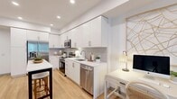 Located at 14817 Foothill Blvd in Fontana, California, this thoughtfully designed one-bedroom, one-bathroom residence offers a cohesive open-concept layout bathed in a clean, modern aesthetic. Light-toned luxury vinyl plank flooring flows throughout, tying together each area seamlessly.

The kitchen is a standout feature, showcasing floor-to-ceiling white shaker cabinetry, a gray subway tile backsplash, white quartz countertops, and a full suite of stainless steel appliances including a refrigerator, range, microwave, and dishwasher. A freestanding kitchen island with bar seating provides additional prep space and a casual dining option.

The open living area is bright and welcoming, with recessed lighting and a large window that allows natural light to fill the room. The bedroom is a calm, comfortable retreat with a generous window offering outdoor views, a warm neutral palette, and access to two closets with built-in shelving and hanging rods for ample storage.

Additional highlights include a dedicated in-unit laundry area and a private balcony, ideal for outdoor relaxation. The bathroom is clean and modern, consistent with the overall design language of the home. Every detail reflects a well-planned, functional living space suited for contemporary everyday life.