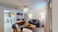 This single-floor, two-bedroom, one-bathroom unit in Mobile, Alabama offers a practical and well-organized layout. The living room serves as the central gathering space, featuring light tile flooring, a textured ceiling, and a ceiling fan with integrated lighting. The open sightline to the kitchen creates a connected feel, while a window near the entry allows natural light to filter in. The kitchen is equipped with warm-toned oak cabinetry, white countertops, a double-basin stainless steel sink, and white appliances, including a refrigerator and stove. A window and secondary door provide additional light and access. Both bedrooms are carpeted and include ceiling fans, windows with curtains, and ample wall space. The primary bedroom features dual windows that bring in natural light, while the second bedroom also benefits from a windowed exterior wall. The shared full bathroom includes tile flooring, a tub-shower combination with white subway tile surround, and a clean, functional design. Throughout the unit, neutral wall colors and consistent finishes contribute to a cohesive and comfortable atmosphere.