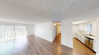 Located on Grand Avenue in San Diego's 92109 zip code, this single-floor unit offers a clean, functional layout designed for comfortable everyday living. The open living area is finished with wood-look flooring and crisp white walls, creating a bright and neutral backdrop. A sliding glass door connects the space to a private balcony, allowing natural light to filter in. A textured ceiling runs throughout the main living areas, adding a subtle architectural detail.

The kitchen is well-appointed with white cabinetry, light stone-style countertops, brushed gold hardware, and a stainless steel refrigerator. Ample cabinet and counter space make the kitchen practical for daily use, and the wood-look flooring continues seamlessly from the living area.

The bedroom offers a quieter retreat, finished with plush carpeting and a large window dressed with vertical blinds that invite natural light while maintaining privacy. A built-in sliding-door closet provides organized storage space.

The bathroom features a tub-shower combination, a single-sink vanity with a light stone countertop, a large mirror, and wood-look flooring, maintaining the unit's cohesive, clean aesthetic throughout. Overall, the unit presents a move-in-ready interior with a consistent, modern feel.