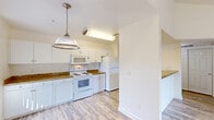 Located at 1711 W Henderson Ave in Porterville, CA, this well-appointed one-bedroom, one-bathroom residence offers a thoughtfully organized single-floor layout. The open-concept kitchen and dining area is a standout feature, showcasing white shaker-style cabinetry, rich granite-look countertops, white appliances including a range, built-in microwave, and refrigerator, plus a stylish pendant light overhead. Light wood-look flooring flows throughout the kitchen, dining, and living areas, creating a bright and cohesive feel. The spacious living room features vaulted ceilings, a ceiling fan, and a sliding glass door that opens onto a private balcony with outdoor views. The bedroom is carpeted for comfort, includes a ceiling fan, and is served by three closets for ample storage. The full bathroom mirrors the kitchen's design aesthetic with granite-look counters, white cabinetry, and a tub/shower combination. Additional conveniences include a dedicated laundry area, a pantry, a utility room, and a hallway connecting the spaces efficiently. The unit's clean, neutral palette and consistent finishes create a cohesive and move-in-ready living environment.
