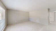 Located at 855 Greens Rd in Houston, TX, this single-floor 2-bedroom, 2-bathroom unit offers a clean, neutral aesthetic throughout. Light-toned tile flooring flows consistently across all living areas, creating a bright and cohesive feel.

The combined kitchen and living area forms the heart of the unit. The kitchen is equipped with gray shaker-style cabinetry, marble-look countertops, a peninsula with a bold range hood overhead, and stainless steel and black appliances including a refrigerator and electric range. A window above the sink brings in natural light. The adjacent living room is open and well-lit, featuring a sliding glass door that leads to an outdoor area, allowing additional natural light and exterior views.

The primary bedroom is generously sized with its own closet access, while the second bedroom features a window with views of the surrounding exterior. Both rooms carry the same light tile flooring and neutral wall tones found throughout the unit. A hallway connects the bedrooms to the rest of the layout.

Both bathrooms are finished with white tile tub-shower combinations, chrome fixtures, and marble-patterned vanity surfaces, maintaining the clean, uniform palette of the home. The overall ambiance is bright, minimal, and move-in ready.