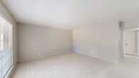 Located at 855 Greens Rd in Houston, TX, this single-floor 2-bedroom, 2-bathroom unit offers a clean, neutral aesthetic throughout. Light-toned tile flooring flows consistently across all living areas, creating a bright and cohesive feel.

The combined kitchen and living area forms the heart of the unit. The kitchen is equipped with gray shaker-style cabinetry, marble-look countertops, a peninsula with a bold range hood overhead, and stainless steel and black appliances including a refrigerator and electric range. A window above the sink brings in natural light. The adjacent living room is open and well-lit, featuring a sliding glass door that leads to an outdoor area, allowing additional natural light and exterior views.

The primary bedroom is generously sized with its own closet access, while the second bedroom features a window with views of the surrounding exterior. Both rooms carry the same light tile flooring and neutral wall tones found throughout the unit. A hallway connects the bedrooms to the rest of the layout.

Both bathrooms are finished with white tile tub-shower combinations, chrome fixtures, and marble-patterned vanity surfaces, maintaining the clean, uniform palette of the home. The overall ambiance is bright, minimal, and move-in ready.