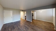 Located at 201 Cairn Cir in Knoxville, Tennessee, this single-floor residence offers a well-designed layout with thoughtful updates throughout. The open living and dining area is finished with rich, dark hardwood-style flooring and neutral gray walls, creating a clean and contemporary atmosphere. A sliding glass door floods the space with natural light and provides direct access to an outdoor patio area with a stone backdrop. The textured ceiling adds a classic residential character throughout the main living spaces.

The kitchen is a standout feature, outfitted with white shaker-style cabinetry, granite-look countertops, and a white subway tile backsplash. Stainless steel appliances, including a refrigerator, range, and dishwasher, complete the modern, functional design. The kitchen connects seamlessly to the main living area, enhancing the open flow of the floor plan.

Bedrooms are carpeted with soft, neutral tones and are served by windows with blinds that allow for natural light while maintaining privacy. A hallway with additional cabinetry and storage connects the rooms efficiently. The overall design balances practicality with updated finishes, making this a well-appointed single-level residence in a convenient Knoxville location.