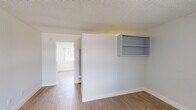 Located at 4901 Clair Del Ave in Long Beach, California, this single-floor unit offers a clean, functional layout designed for comfortable everyday living. The main living area is bright and open, featuring warm wood-look laminate flooring, neutral white walls, and a textured ceiling. A large front-facing window allows natural light to fill the space, creating an airy atmosphere. Built-in wall shelving provides convenient storage and display options directly within the living area.

The kitchen is efficiently appointed with white shaker-style cabinetry extending to the upper and lower levels, dark stone-look countertops, a stainless steel single-basin sink, and a stainless steel gas range with overhead ventilation hood. The layout maximizes counter and storage space for practical use.

A hallway connects the living areas to the bathroom, which features a wide vanity with a single sink, a large wall-spanning mirror, and bright overhead lighting. The bathroom also includes a full-size soaking tub with a shower overhead, a safety grab bar, and a small window for natural ventilation.

Throughout the unit, the consistent use of light tones, clean finishes, and wood-look flooring creates a cohesive and well-maintained interior that is move-in ready.