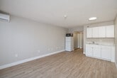 Located at 17065 W Bernardo Dr in San Diego's Rancho Bernardo community, this efficiently designed unit offers a practical and comfortable layout across a single floor. The open living area features light wood-style flooring, neutral gray walls, and a textured ceiling, creating a clean and airy atmosphere. A large picture window with vertical blinds and a valance fills the room with natural light and offers views of surrounding greenery, while a wall-mounted mini-split unit provides climate control. The kitchenette area is neatly appointed with white upper and lower cabinetry, a countertop sink with a light stone surface, and space for a full-size refrigerator and microwave — offering functional everyday convenience within a compact footprint. A hallway connects the main living space to a dedicated closet, providing essential storage. The bathroom is a standout feature, showcasing an extended granite-topped vanity with an undermount sink, a large mirror with wall-mounted lighting, and clean tile flooring — lending a refined touch to the overall space. The unit's straightforward layout and quality finishes make it a practical and well-appointed space in the desirable Rancho Bernardo area of San Diego, CA.