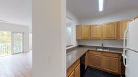 Located at 287 Chauncy St in Mansfield, Massachusetts, this single-floor residence offers a clean, functional layout with consistent finishes throughout. The living area is bright and open, showcasing light wood-style flooring that runs throughout the main spaces, crisp white walls, and generous windows that invite abundant natural light and offer views of the surrounding tree-lined scenery. A sliding glass door opens to a private balcony, further connecting the interior to the outdoors.

The kitchen is thoughtfully designed with warm honey-toned cabinetry featuring arched door detailing, dark granite-style countertops, dark tile flooring, and a full suite of appliances including a gas range, dishwasher, and refrigerator. A pass-through opening connects the kitchen to the main living space, lending an open and airy feel to the layout.

The bedrooms are well-sized and filled with natural light from large windows overlooking lush foliage, continuing the wood-style flooring found throughout the home.

Two full bathrooms serve the residence. One features a combined tub and shower with sliding glass enclosure, a wood vanity with dark countertop, and dark slate-style tile flooring. The second bathroom offers a standalone glass-enclosed shower, a mirrored medicine cabinet, and matching tile and vanity finishes, providing a cohesive and polished aesthetic.
