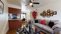 This single-floor residence offers a well-organized layout designed for comfortable everyday living. The living room serves as the heart of the home, featuring warm hardwood-style flooring, a ceiling fan, and ample space for seating. Natural light filters through large windows dressed with draping curtains, creating a welcoming ambiance throughout the shared living areas.

The kitchen is efficiently designed with rich cherry wood cabinetry, granite-style countertops, and black appliances including a refrigerator, electric range, and built-in microwave. A compact dining area adjoins the kitchen, making it ideal for casual meals.

The two bedrooms are carpeted for comfort and each offer a cozy, restful atmosphere. One bedroom features neutral gray walls and generous floor space, while the second is bright and airy with window treatments that allow soft natural light. Both rooms are well-suited for relaxing retreats.

The two bathrooms echo the home's warm aesthetic, featuring hardwood-style flooring, cherry wood vanities with granite-style countertops, and shower-tub combinations with decorative curtains. Clean white walls and tasteful accents keep the spaces feeling fresh and functional. Overall, this residence delivers a cohesive, inviting atmosphere with practical finishes throughout.