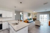 Located at 4 Lantern Ln in Falmouth, MA, this well-appointed 2-bedroom, 2-bathroom single-floor residence offers a thoughtfully designed layout with a clean, contemporary aesthetic throughout. The heart of the home is a bright, open-concept space that seamlessly integrates the kitchen, dining, and living areas. The kitchen is a standout feature, showcasing white shaker cabinetry, quartz countertops, stainless steel appliances — including a French door refrigerator and microwave — and a large center island with seating for three, illuminated by stylish pendant lighting. Durable wood-look flooring extends throughout the main living areas, while recessed and pendant lighting add warmth and depth.

The living area provides comfortable room for seating and a dedicated workspace, with natural light filtering in through windows. Both bedrooms are carpeted for comfort; the primary bedroom is generously sized and features a walk-in closet with wire shelving, an en-suite bathroom with dark cabinetry vanity, and a window with exterior views. The second bedroom also offers ample natural light and closet access. A combined bathroom and laundry room houses a stacked washer and dryer unit alongside a full bath with a tub-shower combo. Additional storage is provided through hallway closets and a pantry, rounding out a highly functional floor plan.