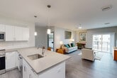 Located at 4 Lantern Ln in Falmouth, MA, this well-appointed 2-bedroom, 2-bathroom single-floor residence offers a thoughtfully designed layout with a clean, contemporary aesthetic throughout. The heart of the home is a bright, open-concept space that seamlessly integrates the kitchen, dining, and living areas. The kitchen is a standout feature, showcasing white shaker cabinetry, quartz countertops, stainless steel appliances — including a French door refrigerator and microwave — and a large center island with seating for three, illuminated by stylish pendant lighting. Durable wood-look flooring extends throughout the main living areas, while recessed and pendant lighting add warmth and depth.

The living area provides comfortable room for seating and a dedicated workspace, with natural light filtering in through windows. Both bedrooms are carpeted for comfort; the primary bedroom is generously sized and features a walk-in closet with wire shelving, an en-suite bathroom with dark cabinetry vanity, and a window with exterior views. The second bedroom also offers ample natural light and closet access. A combined bathroom and laundry room houses a stacked washer and dryer unit alongside a full bath with a tub-shower combo. Additional storage is provided through hallway closets and a pantry, rounding out a highly functional floor plan.