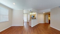 This single-floor residence offers a cohesive, well-designed layout that balances open communal areas with private living spaces. The main living and dining area is finished with warm hardwood-style flooring and accented by crown molding throughout, creating a polished, unified aesthetic. Recessed lighting and neutral warm-beige walls contribute to a bright, inviting atmosphere, while a sliding glass door with vertical blinds allows natural light to flow into the space and provides access to the outdoors.

The kitchen is positioned behind a peninsula-style breakfast bar with granite countertops, offering both visual separation and functional counter seating. Light maple cabinetry pairs with stainless steel appliances, including an electric range and over-the-range microwave, while a diamond-patterned tile backsplash adds a decorative touch. The kitchen also features a undermount sink and ample storage throughout.

The bedrooms are carpeted for comfort and feature crown molding, ceiling fixtures, and windows fitted with horizontal blinds that allow for natural light and privacy. The bathroom is finished with hardwood-style flooring, a granite-topped vanity with light maple cabinetry, and a full soaking tub surrounded by classic white subway tile, completing the space with a clean, timeless look.