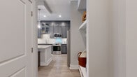 This single-floor residence offers a thoughtfully designed layout across one bedroom and two bathrooms, making efficient use of its compact footprint. The open-concept kitchen and living area serves as the heart of the home, anchored by a striking kitchen with floor-to-ceiling charcoal grey cabinetry, a white quartz waterfall island with seating, stainless steel appliances, a subway tile backsplash, and glass pendant lighting. A dedicated wet bar area with a wine rack adds an upscale touch. Light hardwood flooring flows throughout, contributing to a cohesive and airy aesthetic.

The living room offers recessed lighting, large windows that invite natural light, and direct access to an exterior door. The bedroom is an intimate retreat featuring a window with outdoor views and access to a well-organized walk-in closet. The bathroom showcases grey cabinetry with white countertops, marble-look tile flooring, and a glass-enclosed tiled shower. The entrance includes built-in open shelving for convenient storage. Overall, the space balances modern, high-end finishes with a functional and comfortable layout.