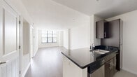 Located at 1028 Walter Reed Drive in Arlington, Virginia, this thoughtfully designed single-floor residence offers a clean, contemporary aesthetic throughout. The open-concept living and dining area is anchored by large, multi-pane windows that flood the space with natural light and offer pleasant views of surrounding greenery. Light-toned hardwood-style flooring flows seamlessly through the main living areas, enhancing the bright and airy atmosphere.

The galley-style kitchen is well-equipped with dark espresso cabinetry, sleek black granite countertops, stainless steel appliances including a refrigerator, oven, and built-in microwave, and a functional peninsula that connects to the living space. Track lighting overhead adds a modern touch.

The bedrooms are generously proportioned, each featuring large windows with blinds, plush carpeting, and ceiling fans for year-round comfort. The layout provides a sense of separation between the living and sleeping areas, with a hallway connecting the bedroom to the bathroom. The bathroom includes neutral tile flooring, contemporary cabinetry with ample storage, and chrome fixtures. Throughout the unit, a consistent neutral color palette and clean architectural lines contribute to a polished, move-in-ready feel.
