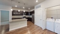 Located at 901 E Oak St in Mahomet, Illinois, this single-floor unit offers a clean, contemporary design with thoughtful finishes throughout. The kitchen serves as a standout feature, boasting rich dark cabinetry, granite countertops, stainless steel appliances including a refrigerator, range, and microwave, and a peninsula with pendant lighting and an undermount sink — ideal for both cooking and casual dining. Hardwood-style luxury vinyl flooring flows throughout the main living areas and kitchen, providing a warm and cohesive aesthetic.

The bedrooms are carpeted for comfort and each include ceiling fans, neutral-toned walls, and windows fitted with blinds that allow for natural light while maintaining privacy. The primary bedroom connects directly to a spacious en-suite bathroom featuring dark vanity cabinetry, granite countertops, hardwood-style flooring, and access to a walk-in closet with built-in shelving. A secondary bathroom mirrors the refined finishes, offering a bathtub with grab bars, a dark vanity with granite countertops, and matching flooring.

Overall, the unit presents a modern, move-in-ready interior with consistent finishes, practical layouts, and a neutral color palette that creates a bright and inviting atmosphere throughout.
