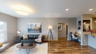 This single-floor residence offers a thoughtfully designed layout that balances comfort and functionality. The living room serves as the heart of the home, featuring warm wood-look flooring, neutral gray walls, recessed lighting, and natural light from large windows. The space flows into a dedicated dining area, accented by a rustic wood table and decorative wall art.

The kitchen is outfitted with white shaker-style cabinetry, granite countertops, stainless steel appliances including a French door refrigerator and electric range, and a double-basin undermount sink — all set along a galley-style layout that maximizes efficiency.

The primary bedroom offers plush carpeting, a ceiling fan, and a window that brings in natural light. It connects to a well-appointed en-suite bathroom featuring a dual-sink vanity with granite countertops, a glass-enclosed shower, tile flooring, and access to a generously sized walk-in closet with built-in shelving. A second bedroom provides comfortable accommodations with its own closet. A dedicated laundry room houses a full-size washer and dryer. The overall aesthetic is cohesive and contemporary, with neutral tones and consistent finishes throughout.
