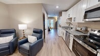 Located at 1551 Johnson Ferry Rd in Marietta, GA, this thoughtfully designed one-bedroom, one-bathroom residence makes excellent use of its compact footprint. Light wood-tone flooring runs throughout, complementing warm neutral wall tones and creating a cohesive, welcoming atmosphere.

The kitchen is fully equipped with stainless steel appliances — including a refrigerator, range, microwave, and dishwasher — paired with crisp white shaker cabinets featuring matte black hardware and granite countertops. The kitchen opens directly to the living area, where recessed lighting enhances the sense of openness.

The living room offers a comfortable, functional layout with space for seating and media, bathed in soft ambient light. A dedicated closet provides practical storage solutions.

The bedroom features a sliding glass door with direct outdoor access, allowing natural light to fill the room. A sliding double-door closet adds convenient in-room storage.

The bathroom is finished with the same granite countertop and white cabinetry found in the kitchen, ensuring design consistency. A shower-tub combination with built-in shelving, wood-look tile flooring, and matte black fixtures complete the space with a clean, modern aesthetic throughout.