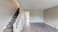 Located at 172 Homestead St in Manchester, CT, this multi-floor residence spans three levels and offers a well-organized layout with a living room, kitchen, bedroom, bathroom, hallway, two closets, and a basement. The main living area welcomes you with light gray luxury vinyl plank flooring, neutral warm-toned walls, and a crisp white staircase railing. Large windows allow natural light to fill the space, creating a bright and airy atmosphere. The kitchen is outfitted with white cabinetry, a tile backsplash, stainless steel appliances including a refrigerator, range, and dishwasher, and flows openly into the living area. The generously sized bedroom is carpeted for comfort and features a wall-mounted air conditioning unit, baseboard heating, and ample natural light through large windows. A walk-in style closet with dual shelving rods provides excellent storage. The bathroom is clean and functional, featuring vinyl plank flooring, a window for natural ventilation, and baseboard heating. The unfinished basement offers a substantial utility and storage area with painted concrete floors and exposed wooden ceiling joists. Baseboard heating is present throughout the home, ensuring year-round comfort.