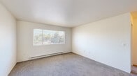 Located at 1915 NE Terre View Dr in Pullman, WA, this two-bedroom, one-bathroom unit offers a functional single-floor layout designed for comfortable everyday living. The living area features neutral carpet flooring, crisp white walls, a textured ceiling, and a wide window fitted with blinds that frames views of mature trees, filling the space with natural light. A baseboard heating system runs along the perimeter, providing consistent warmth throughout. The galley-style kitchen is well-appointed with warm oak cabinetry on both sides, ample counter space, a double-basin sink, and white appliances including a range and refrigerator. Both bedrooms are carpeted and maintain the same clean, neutral palette, each featuring a built-in closet and windows overlooking the surrounding landscape. The primary bedroom includes a roomy closet with a hanging rod, while the second bedroom benefits from views of a natural hillside. The full bathroom includes a tub-shower combo, a wood-vanity with a single sink, a medicine cabinet mirror, and vinyl flooring. A dedicated in-unit laundry room with a full-size washer and dryer rounds out this practical and well-organized home.